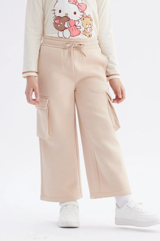 Pantalón buzo beige de corte amplio con bolsillos laterales, ideal para un look casual y cómodo, perfecto para los fans de la cultura pop.