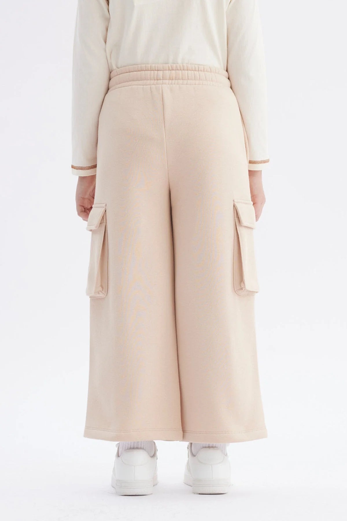 Pantalón buzo beige de corte amplio con bolsillos laterales, ideal para un look casual y cómodo, perfecto para los fans de la cultura pop.