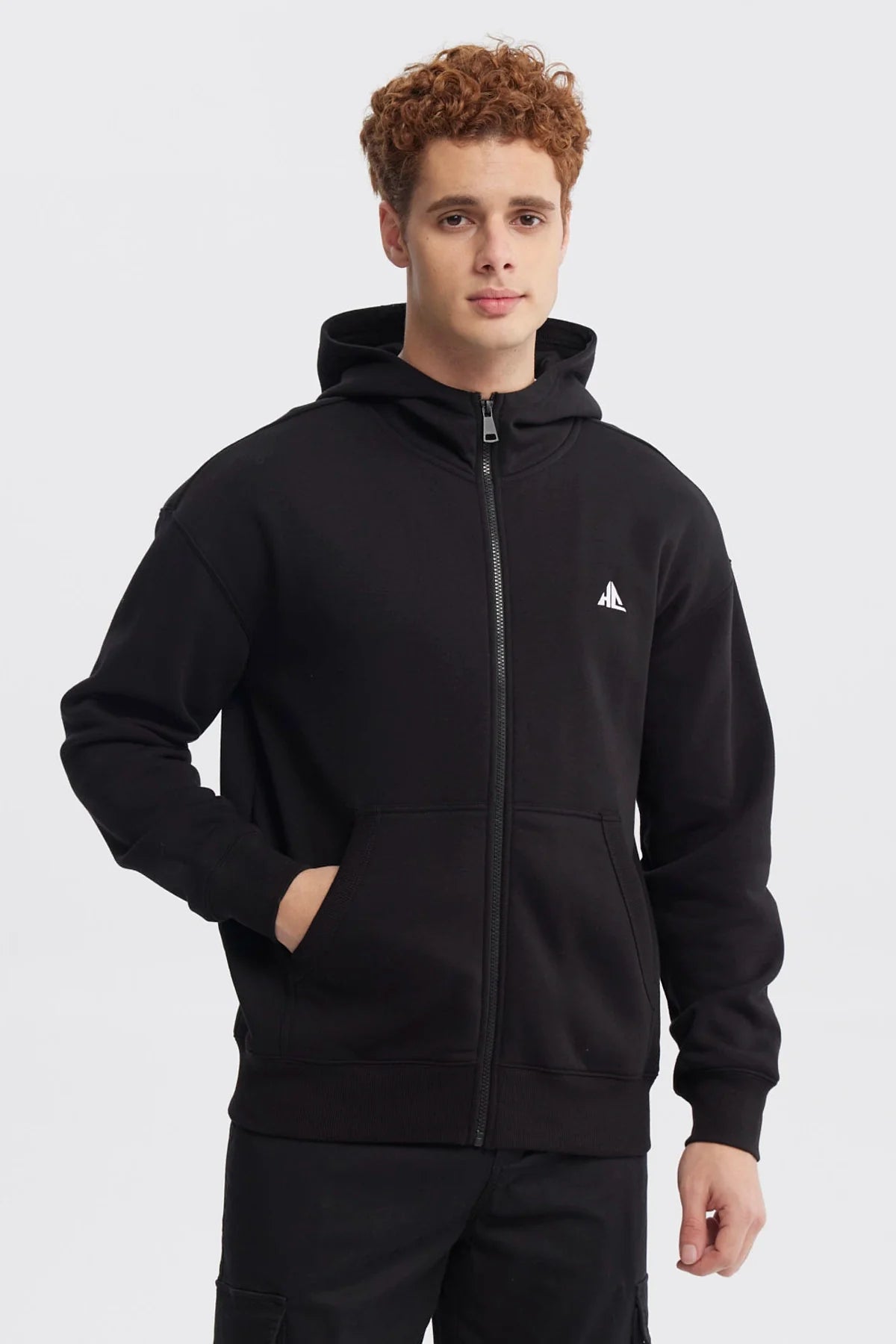 Polerón negro de Holly Concept con cierre frontal y capucha, presenta un logo minimalista en blanco en el pecho, ideal para los fans del estilo urbano.